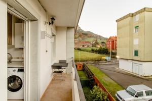 a balcony with a washing machine and a car on a street at apartamento 2 hab - montaña y playa in Gibaja