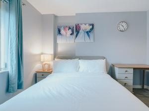 a bedroom with a white bed and a clock on the wall at Jyde Apartments - Sheffield City Centre in Sheffield