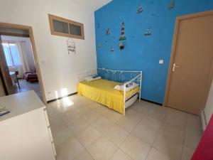 een kamer met een klein bed in een kamer met een blauwe muur bij Chez Cathy et Alain in Saint-Laurent-dʼAigouze