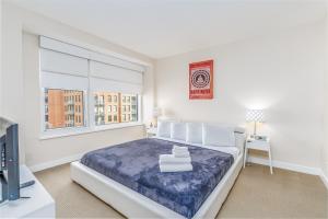 a white bedroom with a large bed and a tv at Furnished 2 Bedroom Apartment near National Museum apts in Washington