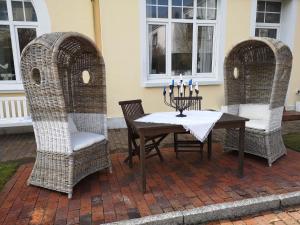 two wicker chairs and a table with candles on it at Haus Strandburg in Wangerooge