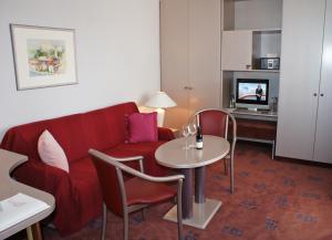 a living room with a red couch and a table at Hotel Garni Lindacher Hof in Burghausen