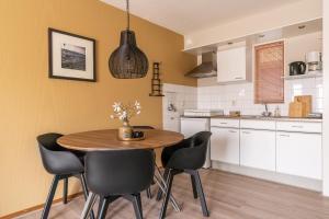 cocina con mesa de madera y sillas negras en Appartement De Bosrand, Resort Amelander Kaap, en Hollum