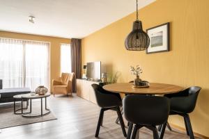 ein Wohnzimmer mit Tisch und Stühlen in der Unterkunft Appartement De Bosrand, Resort Amelander Kaap in Hollum