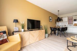 sala de estar con TV, sofá y mesa en Appartement De Bosrand, Resort Amelander Kaap, en Hollum
