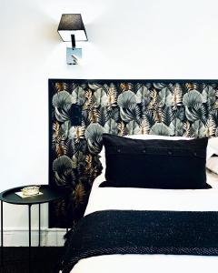 a bedroom with a bed with a black headboard and a table at Hôtel Gaspard in Le Touquet-Paris-Plage