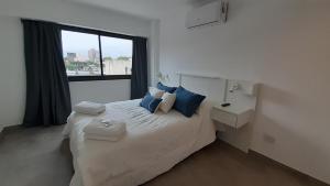 Un dormitorio con una cama con almohadas azules y una ventana en Suites Quality 2 - Rosario en Rosario
