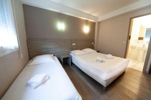 twee bedden in een kleine kamer met een raam bij Hôtel Beaulieu in Clermont-Ferrand