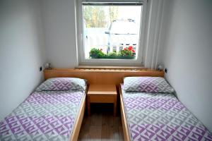 two beds in a small room with a window at Apartma Metka Leše Tržič in Leše