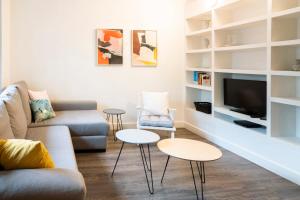 uma sala de estar com um sofá e duas mesas e uma televisão em Casa Cosi - Casanova 2 em Barcelona