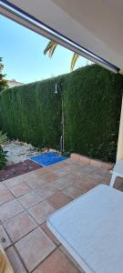 a patio with a green hedge and a blue mat at maison nathalia in Jávea