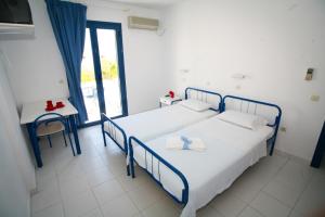 a bedroom with two beds and a table and a window at Gorgona Studios in Livadion