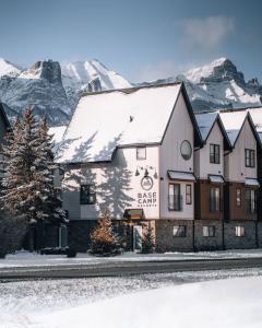 a building with snow covered mountains in the background at Basecamp Resorts Canmore in Canmore