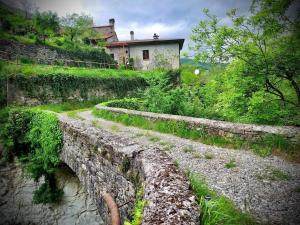 a stone bridge over a river with a house in the background at Le Macine del Perino in Bettola
