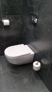 a bathroom with a toilet in a black wall at Apartamenty SIENKIEWICZA 8 in Żywiec