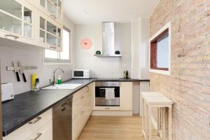 una cocina con armarios blancos y una pared de ladrillo en Casa Cosi - Casanova 6 en Barcelona