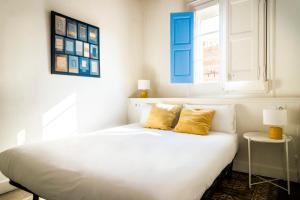 een wit bed met 2 gele kussens in een slaapkamer bij Casa Cosi - La Gleva 4 in Barcelona