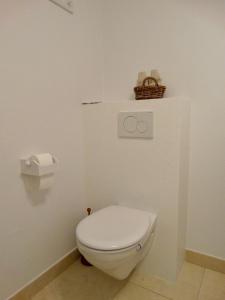 a white toilet in a bathroom with a basket on the wall at BENVENUTI in Sint-Idesbald