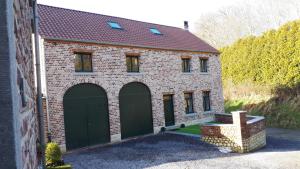 a brick house with two green garage doors at Les Chanterolles in Chaumont-Gistoux