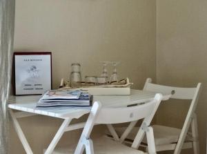 einen weißen Tisch mit zwei weißen Stühlen und einer Schachtel in der Unterkunft BENVENUTI in Saint-Idesbald