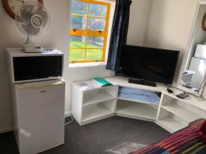 a room with a desk with a television and a fan at Fache Cottage in Clyde