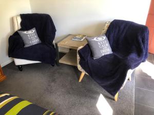 um quarto com duas cadeiras e uma mesa com duas almofadas em Fache Cottage em Clyde