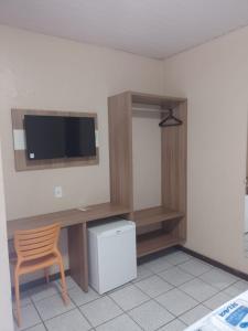 um quarto com uma secretária, uma televisão e uma cadeira em Boulevard Park Hotel em São Luís