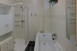 La salle de bains blanche est pourvue d'une baignoire et d'une douche. dans l'établissement Příjemný řadový rodinný dům se zahradou, à Egra