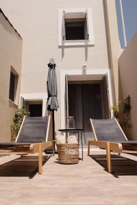 patio z 2 krzesłami, parasolem i stołem w obiekcie Casa di Famiglia Rhodes w mieście Koskinou