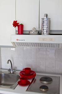 a kitchen counter with a sink and red dishes at Gorgona Studios in Livadion +39 photos