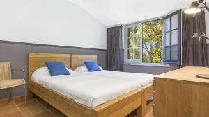 a bedroom with a bed with blue pillows and a window at 1 Past2 - Llafranc in Llafranc