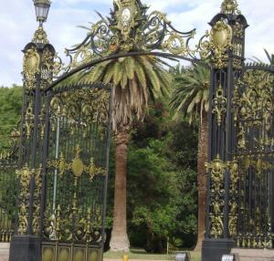 ein goldenes Tor mit einer Palme dahinter in der Unterkunft Departamentos Mendoza in Mendoza