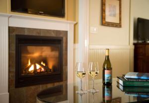 two glasses of white wine on a table with a fireplace at Grand Harbor Inn in Camden