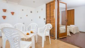 Habitación con sillas blancas, mesa y espejo. en 1Prun01 Llafranc, en Llafranc