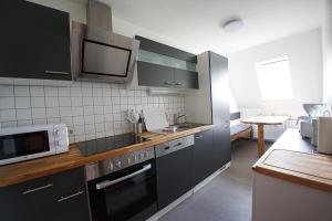 a kitchen with black cabinets and a microwave at Midlum Stieglitz in Midlum