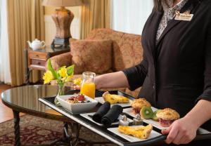 a woman holding a tray of food on a table at Grand Harbor Inn in Camden