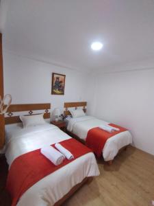 a bedroom with two beds with red and white sheets at Qente Wings in Ollantaytambo
