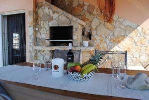 a table with a bowl of fruit and a bottle of wine at Apartments Vidolma in Povljana