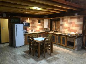 a kitchen with a table and a white refrigerator at Cabañas LA EMILIA Uspallata Mdz in Uspallata