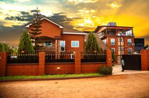 una casa dietro una recinzione con un tramonto sullo sfondo di Homey Lodge a Kumasi