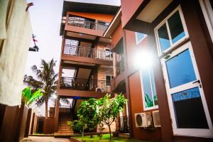an apartment building with balconies and a palm tree at Homey Lodge in Kumasi