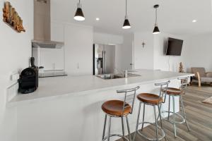 a kitchen with two bar stools and a counter at Sandy Shores - Waihi Beach Holiday Home in Waihi Beach