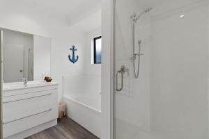 a white bathroom with a shower and a sink at Sandy Shores - Waihi Beach Holiday Home in Waihi Beach +18 photos
