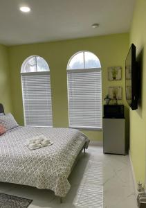 マイアミにあるCasa Miami 1の緑の壁のベッドルーム1室、窓2つ付きのベッド1台が備わります。