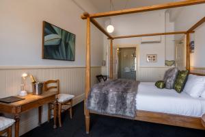 a bedroom with a bed and a desk and a bed and a desk at Hotel D'urville Blenheim in Blenheim