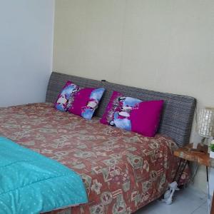 a bed with pink and blue pillows on it at Blesshomestay Samosir in Sinabono
