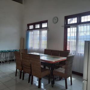 une salle à manger avec une table, des chaises et une horloge dans l'établissement Blesshomestay Samosir, à Sinabono