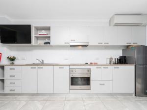 a kitchen with white cabinets and a stainless steel refrigerator at Nesuto Apartments Unit 509 in The Entrance