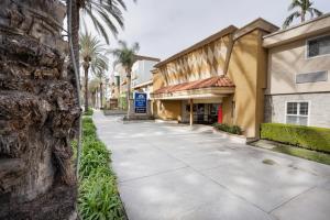 a sidewalk in front of a building with palm trees at Americas Best Value Inn & Suites Anaheim in Anaheim