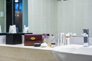 La salle de bains est pourvue d'un lavabo et d'un comptoir avec des produits cosmétiques. dans l'établissement Killara Hotel & Suites, à Killara